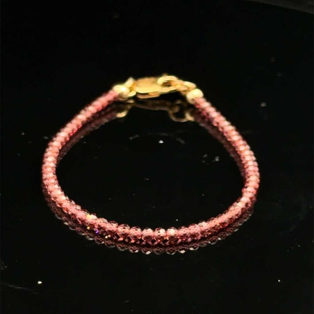 A 2mm micro faceted round Red garnet gemstone beaded bracelet with a gold-filled lobster claw on a black background, front view.