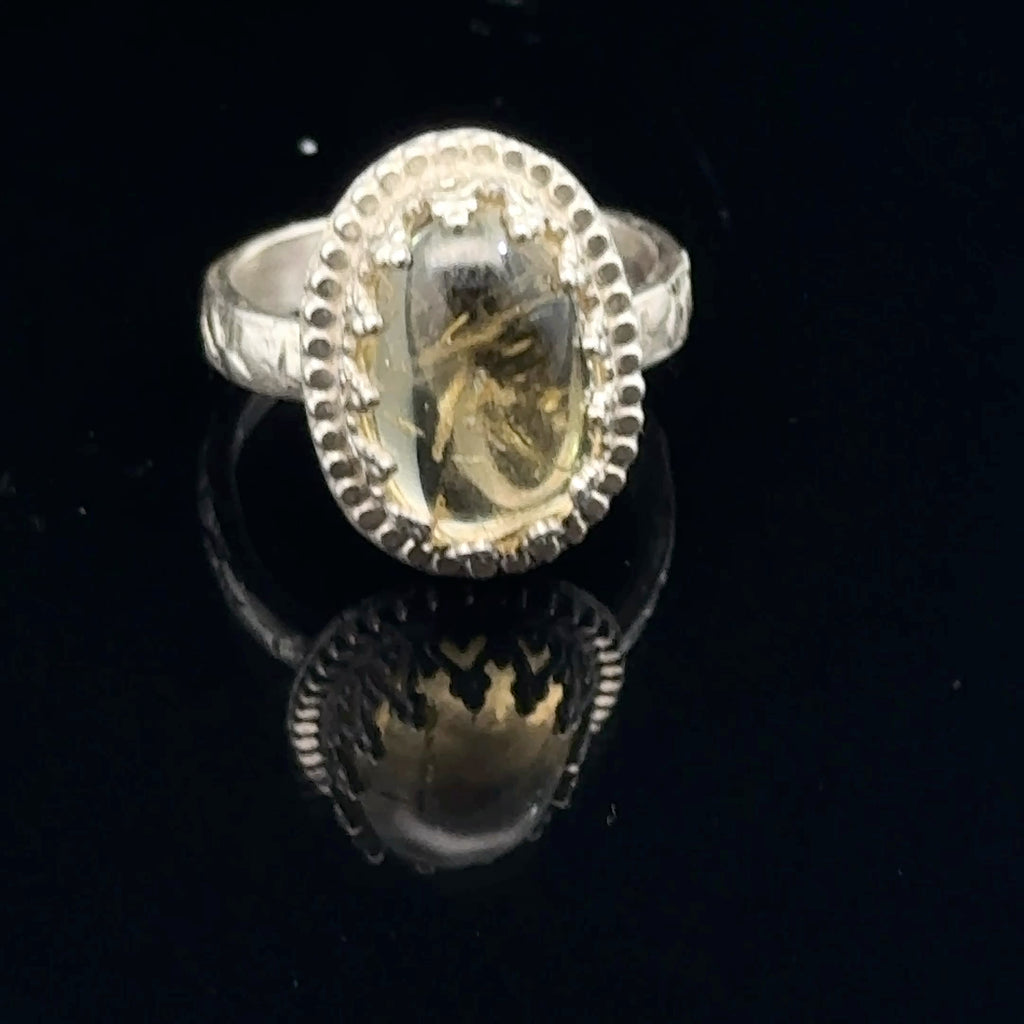 A Citrine Gemstone ring in sterling silver a vintage style on a black background front, close up view. 