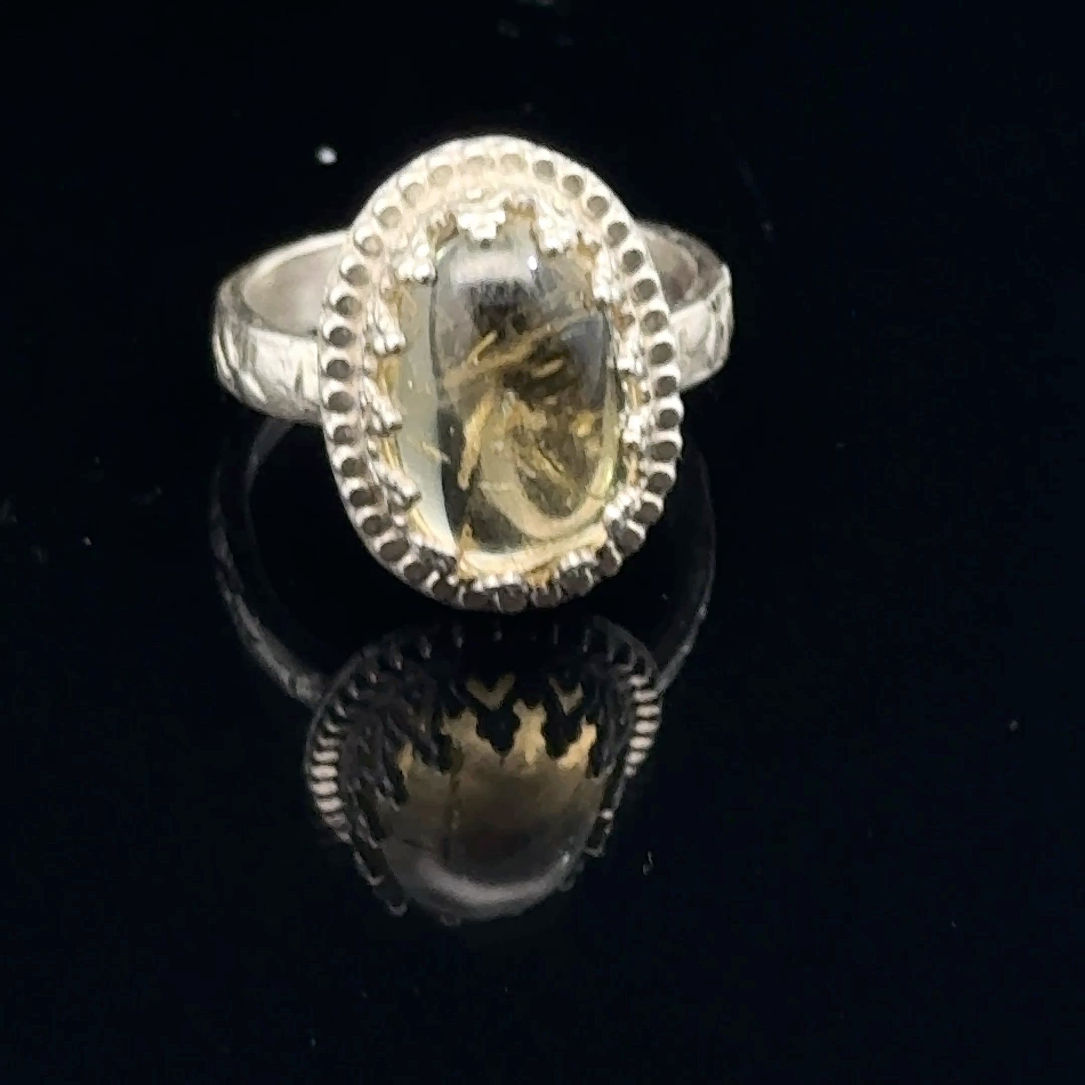 A Citrine Gemstone ring in sterling silver a vintage style on a black background front, close up view. 