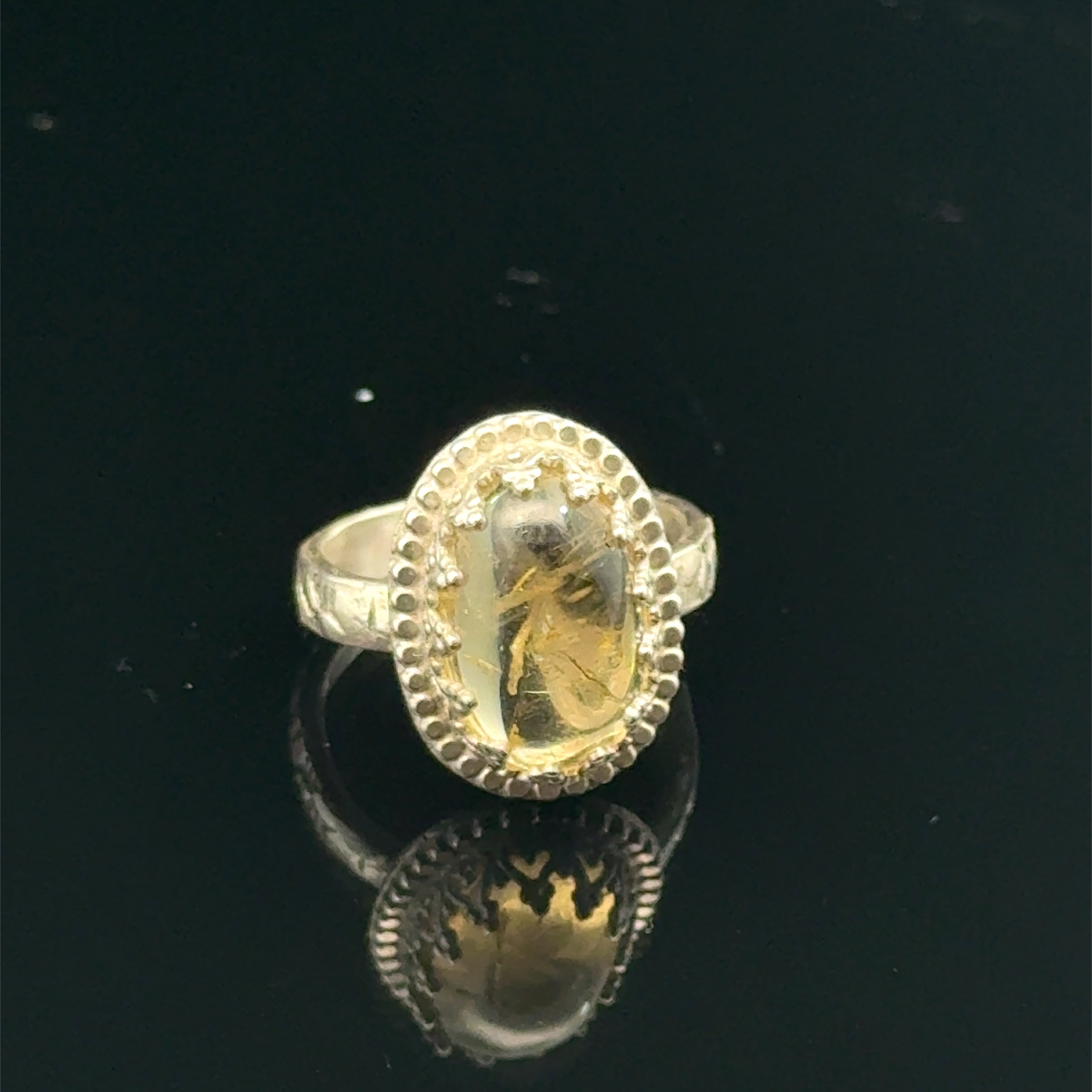 A Citrine Gemstone ring in sterling silver a vintage style on a black background front view. 