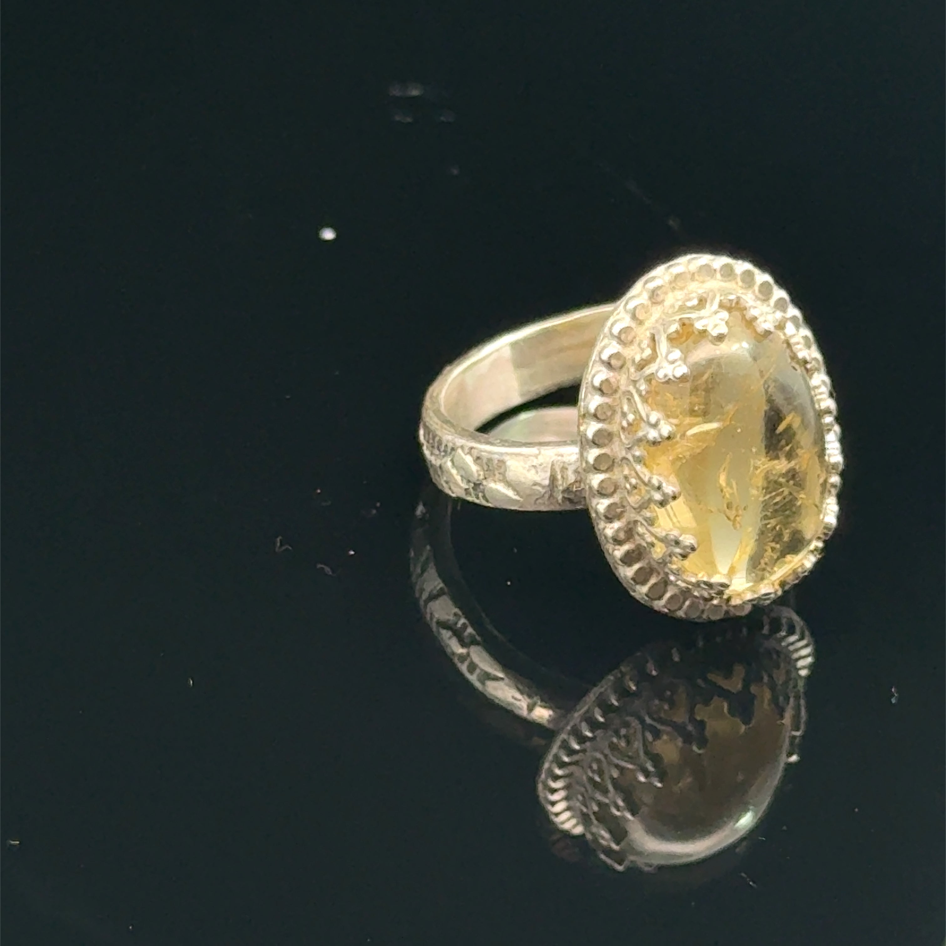 A Citrine Gemstone ring in sterling silver a vintage style on a black background right angle view. 