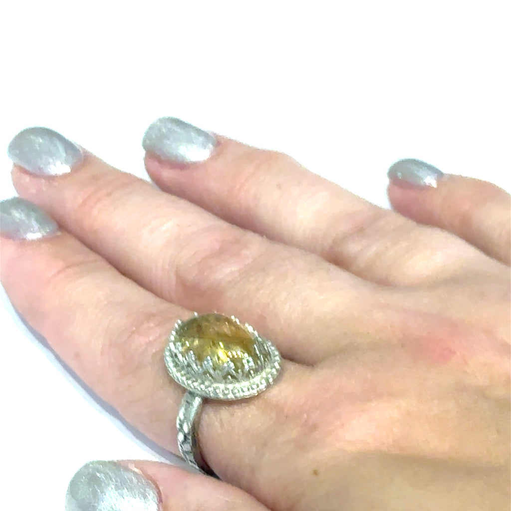 A Citrine Gemstone ring in sterling silver a vintage style on a white background front, close up view in a models finger. 