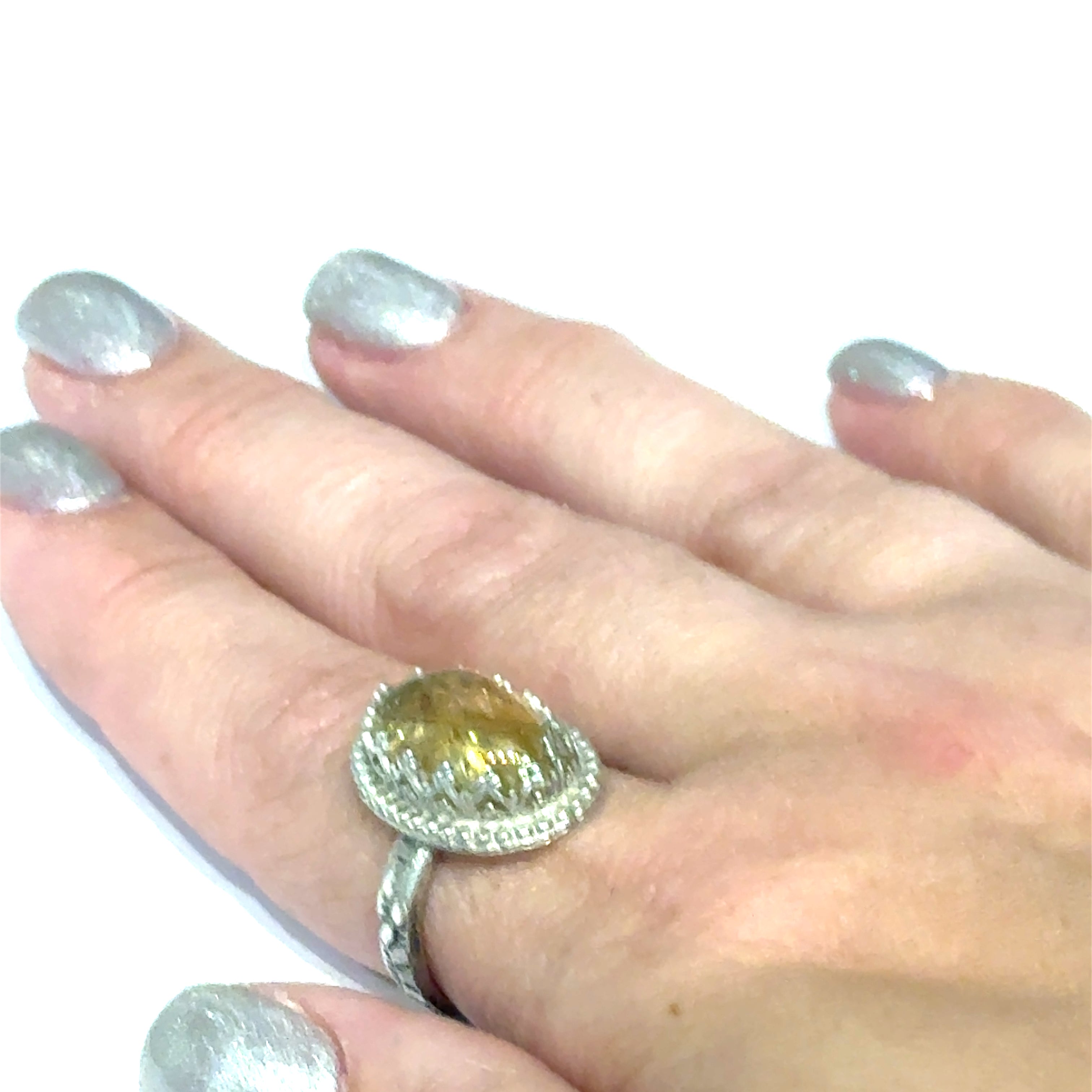 A Citrine Gemstone ring in sterling silver a vintage style on a white background front, close up view in a models finger. 