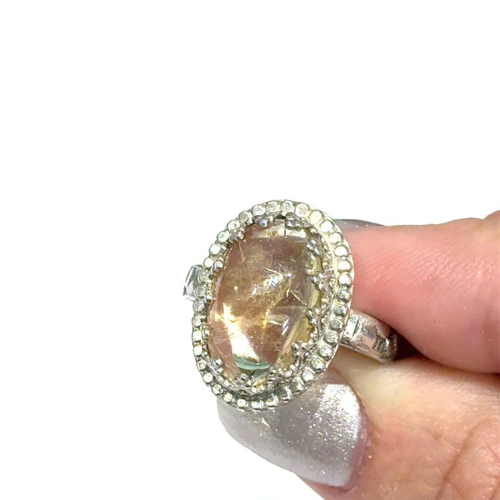 A Citrine Gemstone ring in sterling silver a vintage style on a white background front, close up view in a models finger tips. 