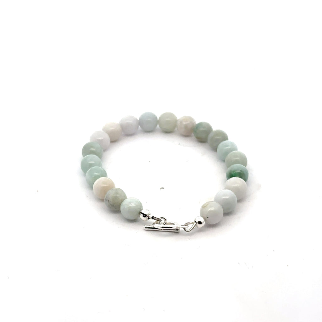 A Close-up of a 6mm polished Burma jade beads showing natural green color and smooth finish on a white back ground, back view. 