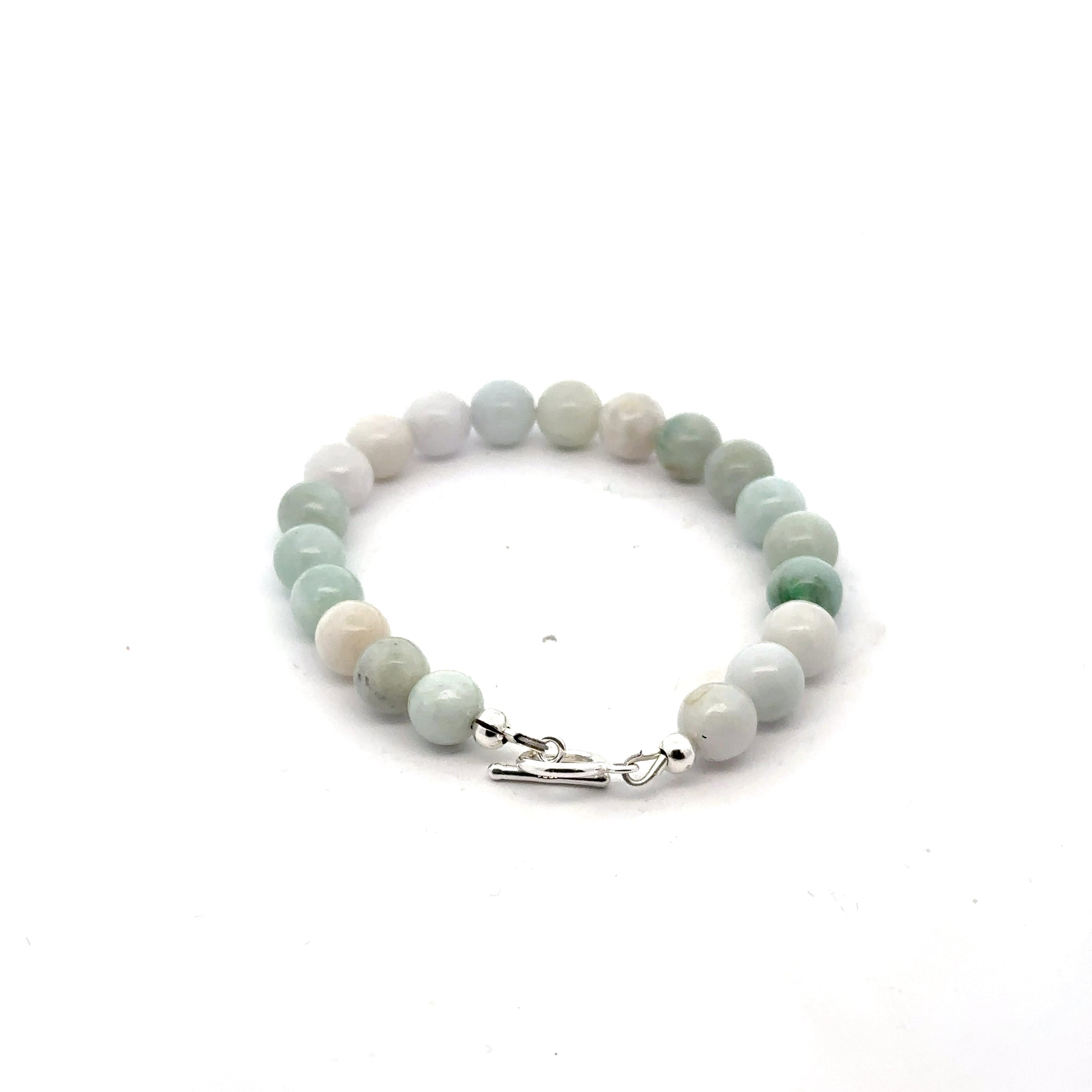 A Close-up of a 6mm polished Burma jade beads showing natural green color and smooth finish on a white back ground, back view. 