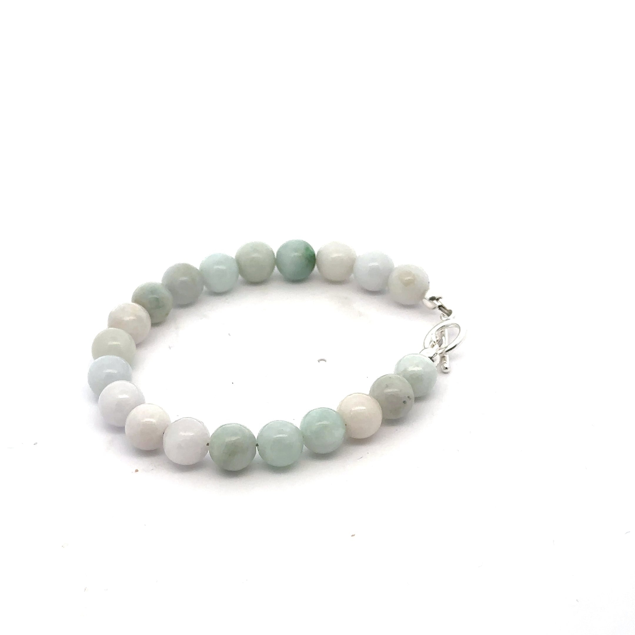 A Close-up of a 6mm polished Burma jade beads showing natural green color and smooth finish on a white back ground, left angle view. 