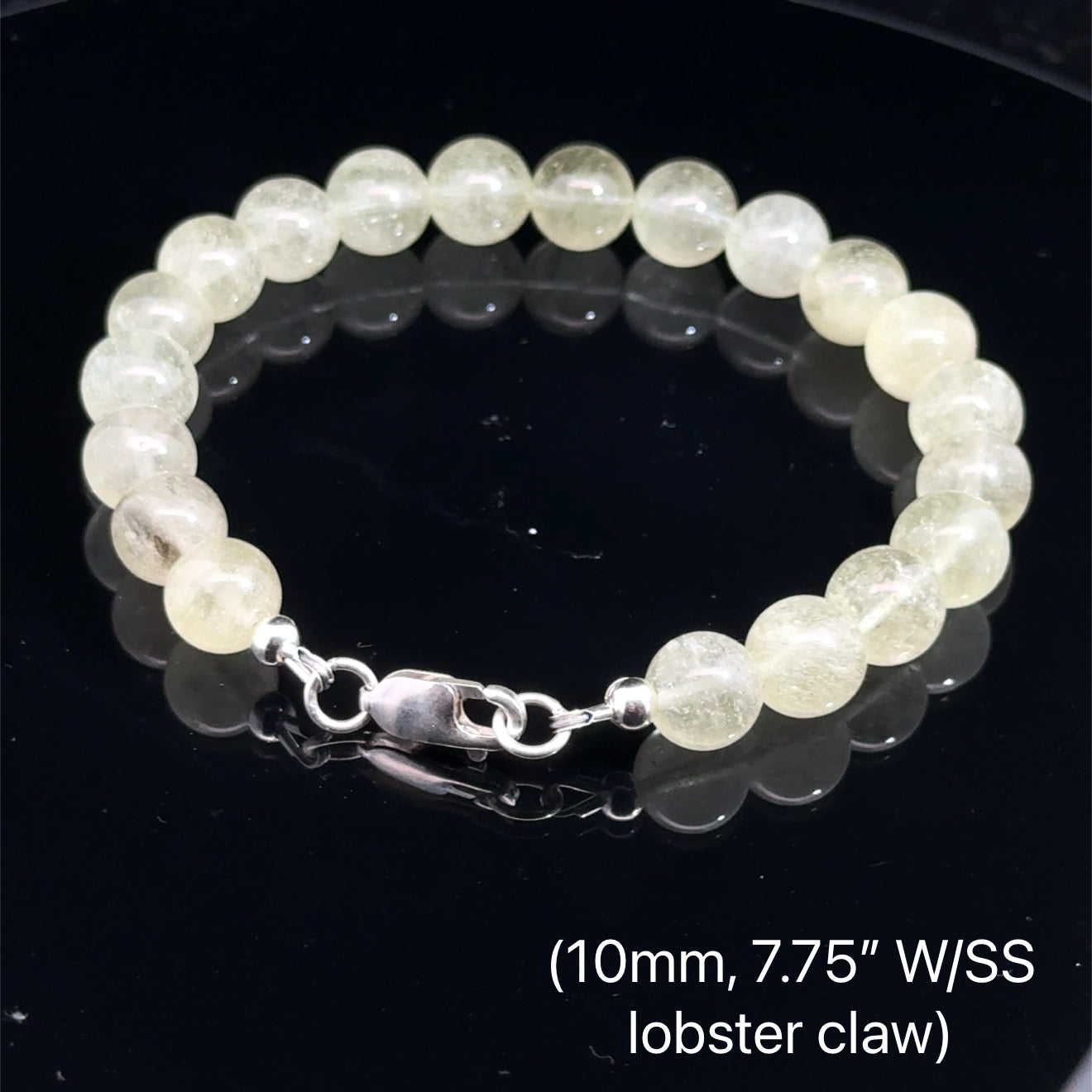 A Close-up of genuine Libyan Desert Glass tektite beads showing translucent golden-yellow color (10mm. 7.75'' w/ sterling silver lobster claw) on a black background, back overview. 