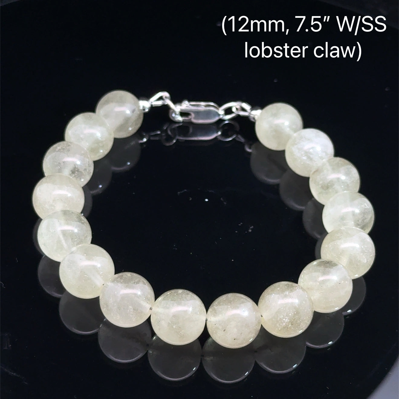 A Close-up of genuine Libyan Desert Glass tektite beads showing translucent golden-yellow color (12mm. 7.5'' w/ sterling silver lobster claw) on a black background, front overview. 