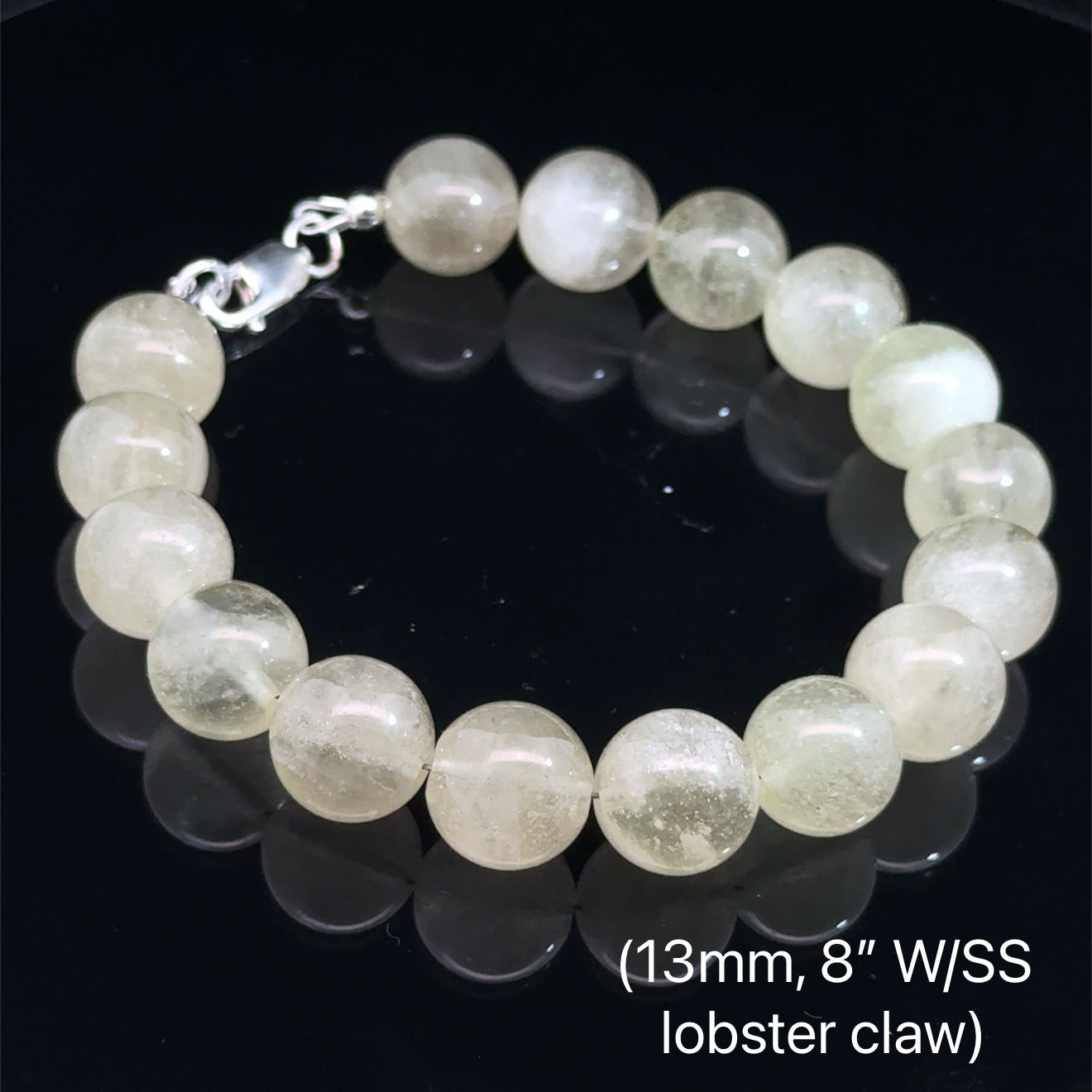 A Close-up of genuine Libyan Desert Glass tektite beads showing translucent golden-yellow color (13mm. 8'' w/ sterling silver lobster claw) on a black background, front overview. 
