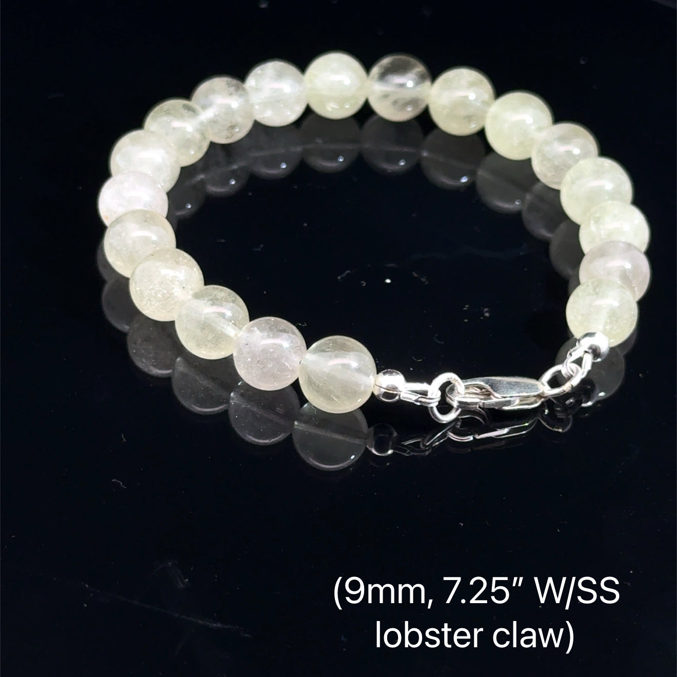 A Close-up of genuine Libyan Desert Glass tektite beads showing translucent golden-yellow color (9mm. 7.25'' w/ sterling silver lobster claw) on a black background, back overview. 