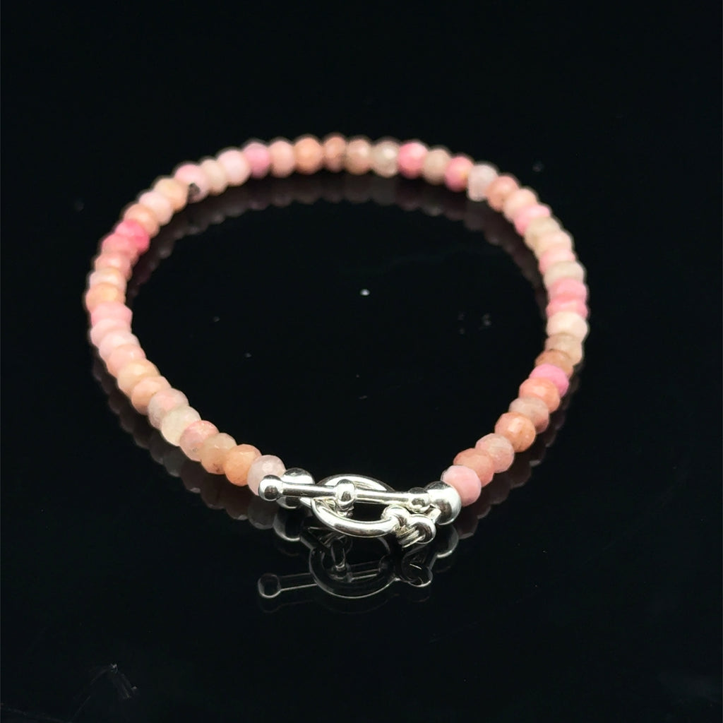 A Rhodochrosite Gemstone 3mm faceted roundel beaded bracelet with a sterling silver toggle, on a black background, back overview.