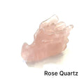 A carved Rose Quartz gemstone in the shape of a dragon's head on a white background, right side view. 