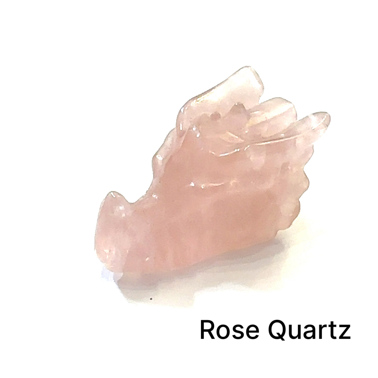 A carved Rose Quartz gemstone in the shape of a dragon's head on a white background, right side view. 