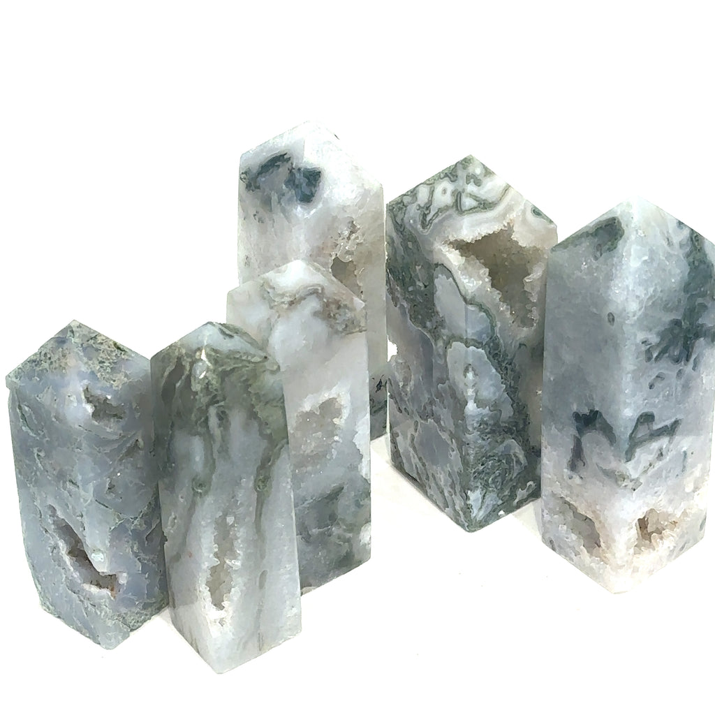A collection of Moss Agate gemstone towers in various shades of green and white, displaying typical moss-like inclusions. On a white background, front overview.