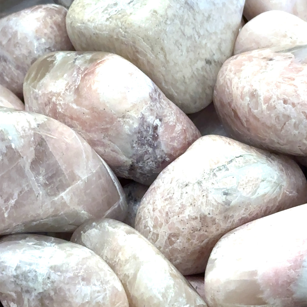 A collection of large tumbled Petalite gemstones with a pink hue, displayed   on a white background, front overview.