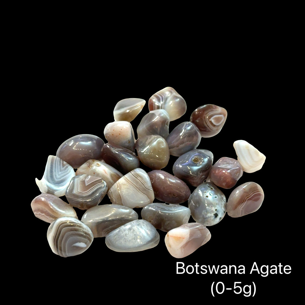 A collection of tumbled Botswana Agate gemstones on a Black background, (0-5g) front view.