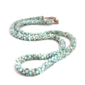 A crocheted necklace made with Larimar gemstone beads and a sterling silver butterfly box clasp on a white background, long front view. 