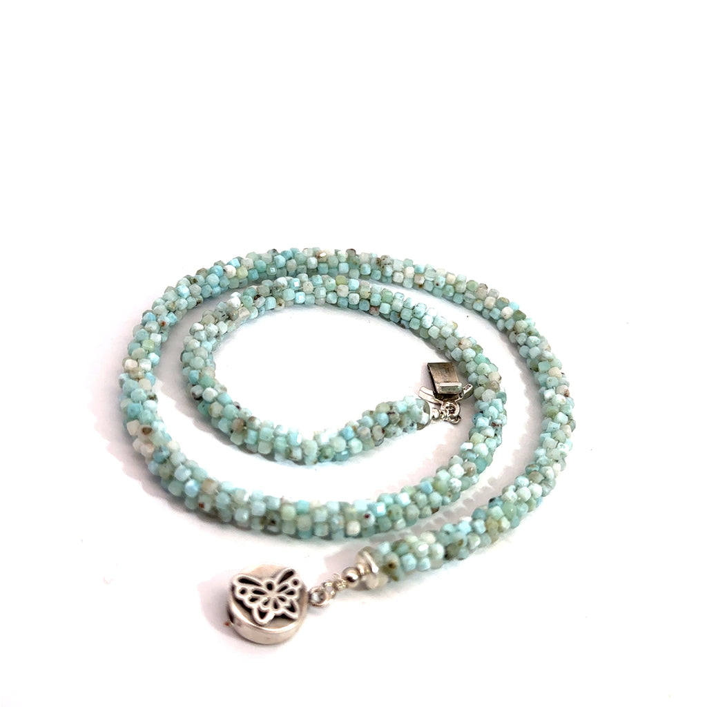 A crocheted necklace made with Larimar gemstone beads and a sterling silver butterfly box clasp on a white background, spiral box clasp close up overview. 