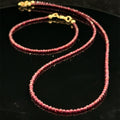 A garnet beaded necklace with its matching bracelet on a black background, front view. 