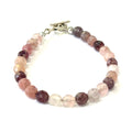 A genuine Strawberry Quartz gemstone bracelet with faceted beads and a aterling silver toggle on a white background, with a front center overview. 