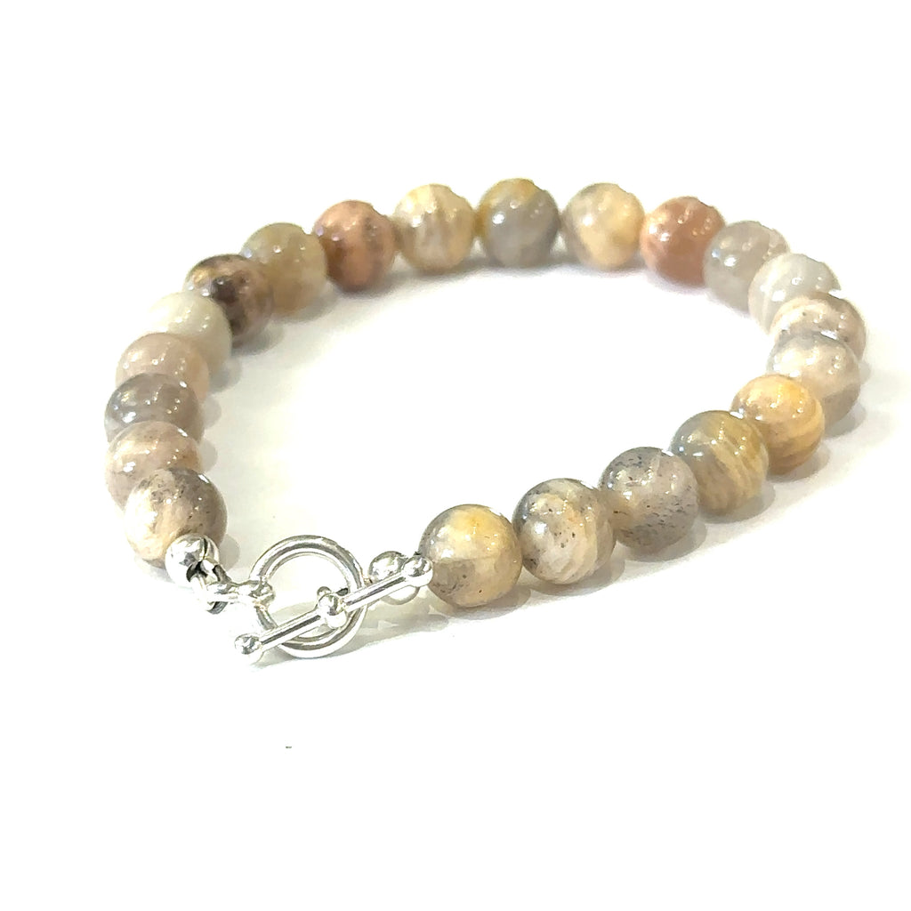 A greyish peach Moonstone gemstone beaded bracelet with a sterling silver toggle clasp on a white background, back, slight left angle overview. 