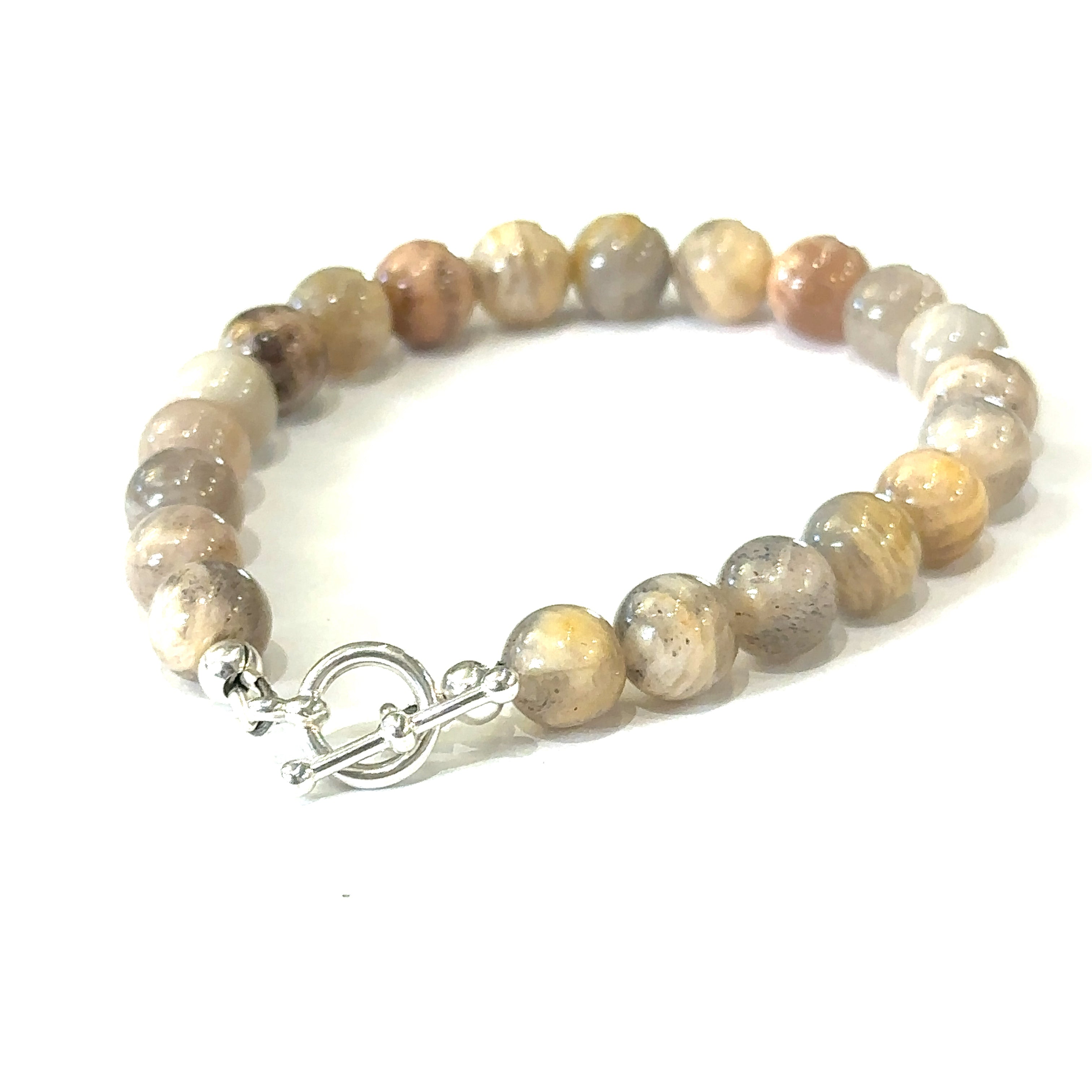 A greyish peach Moonstone gemstone beaded bracelet with a sterling silver toggle clasp on a white background, back, slight left angle overview. 