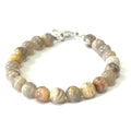 A greyish peach Moonstone gemstone beaded bracelet with a sterling silver toggle clasp on a white background, front overview. 