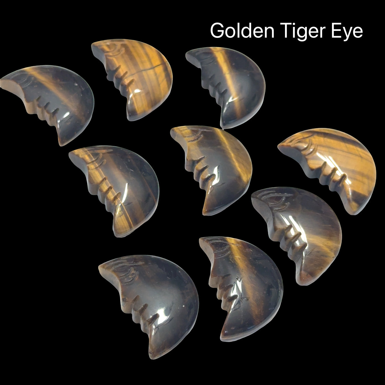 A group of Golden Tiger Eye Gemstone moon carvings on a black background, front view.