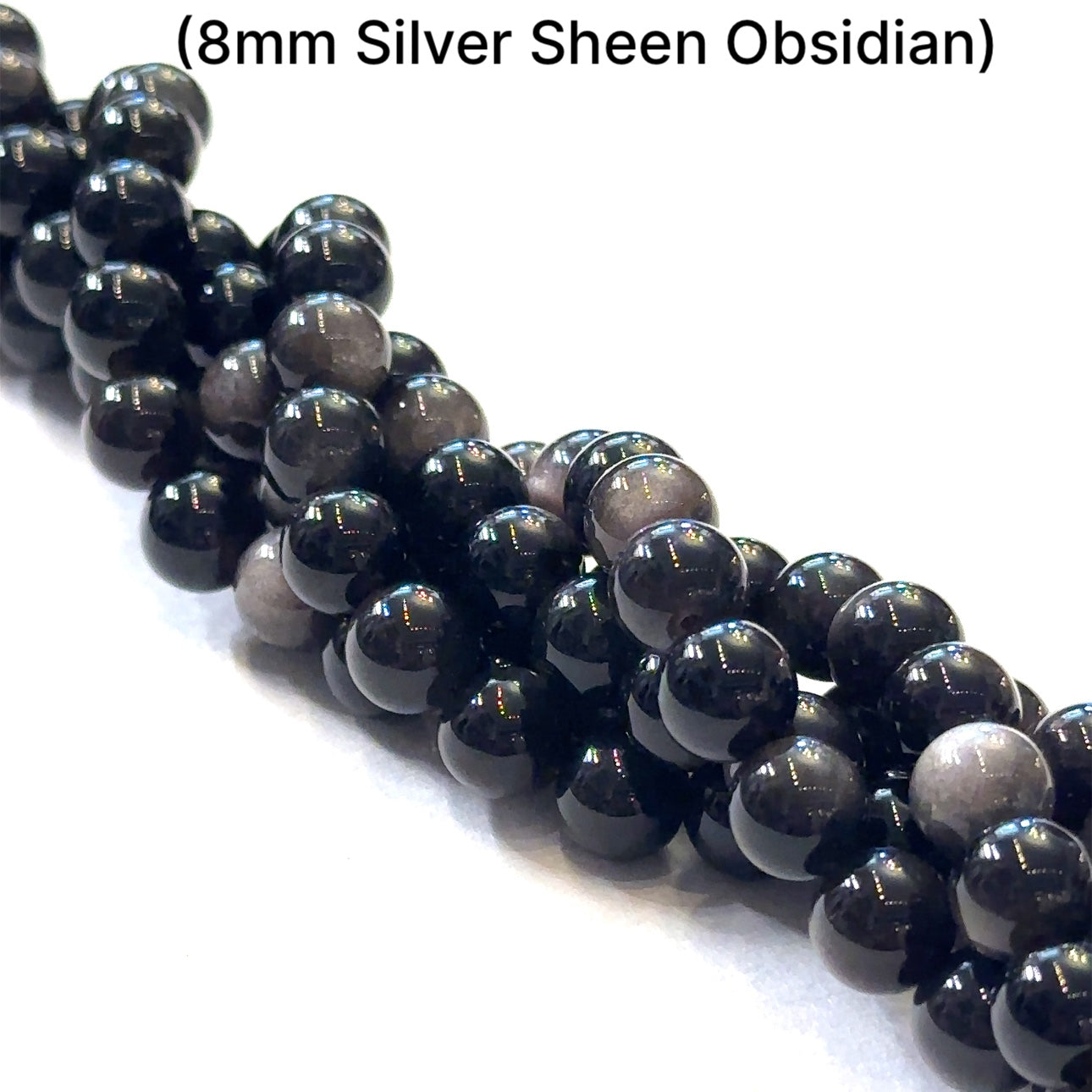 A group of strands of 8mm Silver Sheen Obsidian gemstone beads on a white background, front overview. 