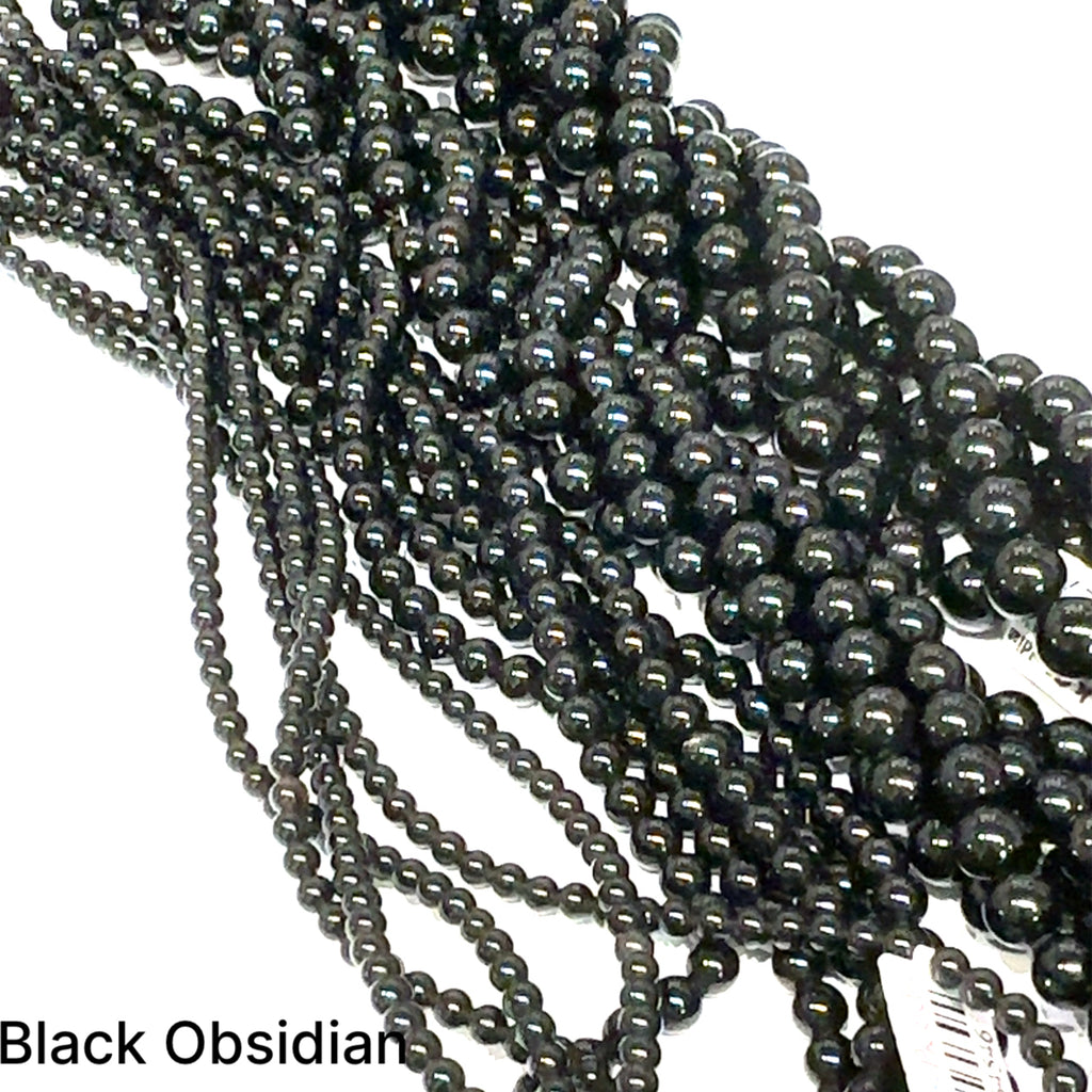 A group of strands of black obsidian gemstone beads on a white background, front overview. 
