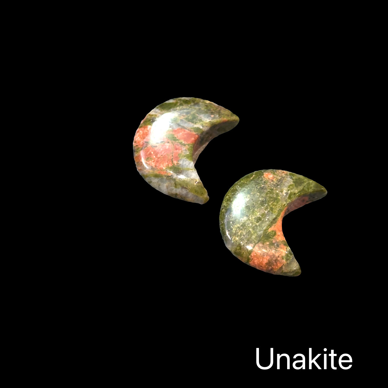 A group of unakite Gemstone moon carvings on a black background, front view.