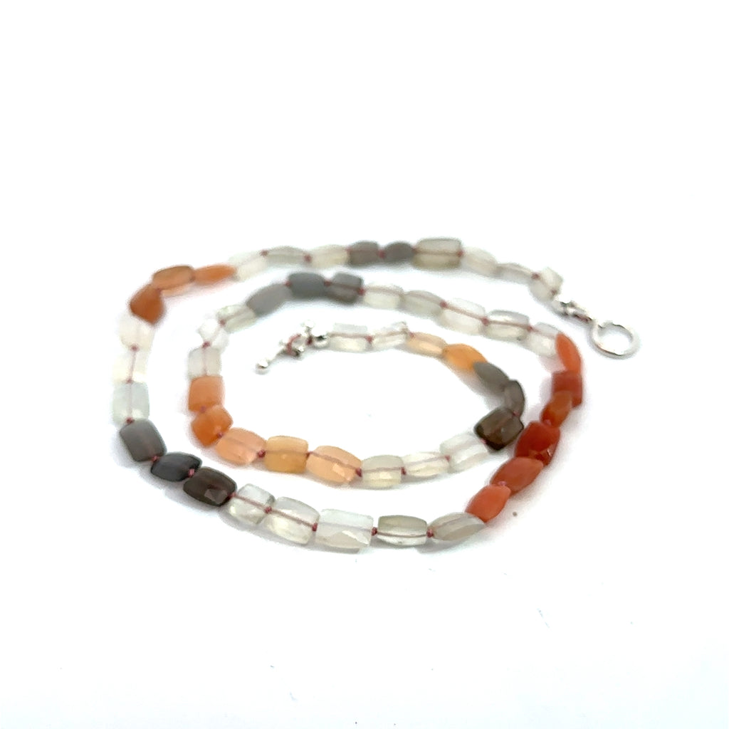 A knotted necklace made of mixed moonstone gemstones with a sterling silver toggle clasp on a white background, spiral front overview 