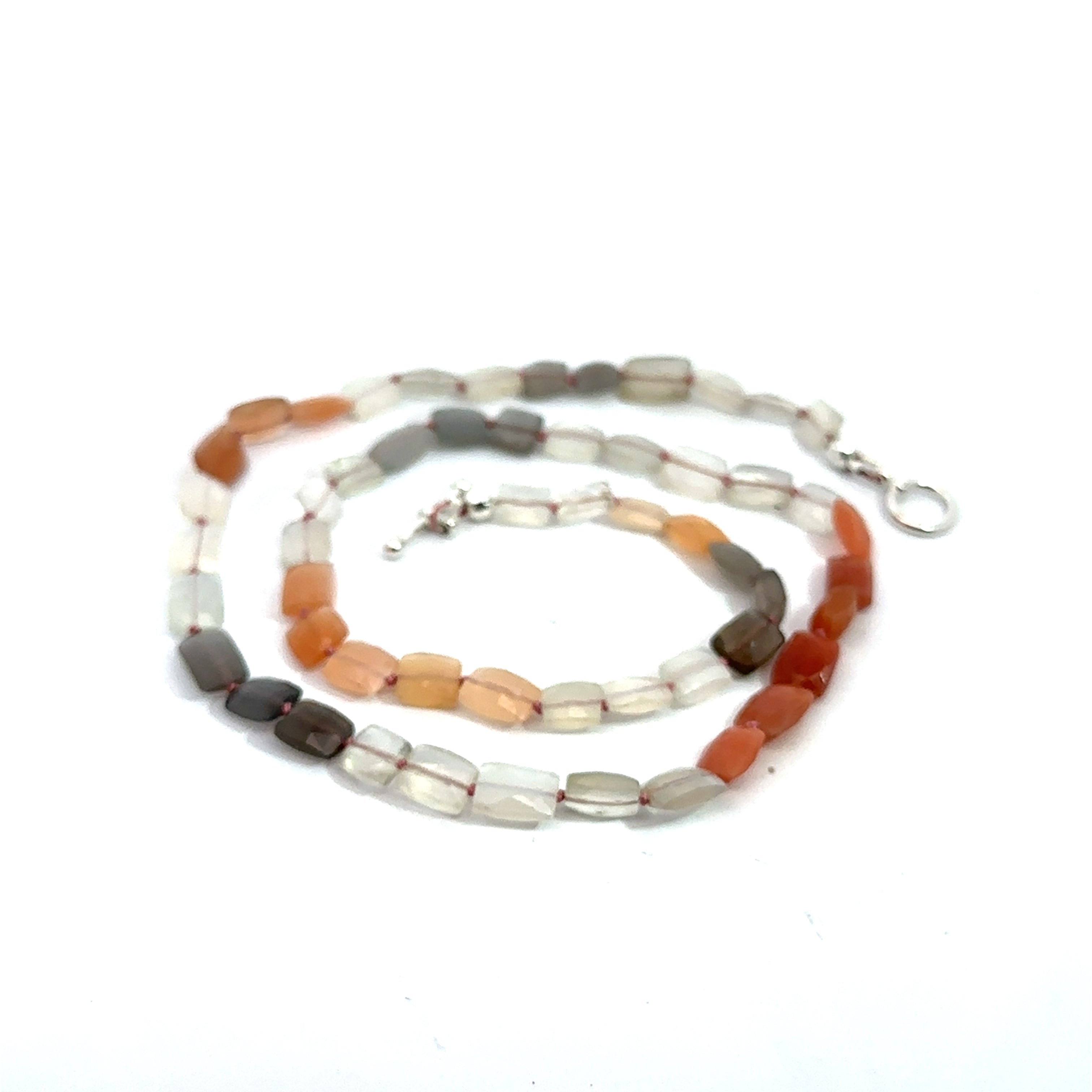 A knotted necklace made of mixed moonstone gemstones with a sterling silver toggle clasp on a white background, spiral front overview 