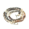 A mixed moonstone faceted roundel knotted necklace on a white background, spiral overview. 
