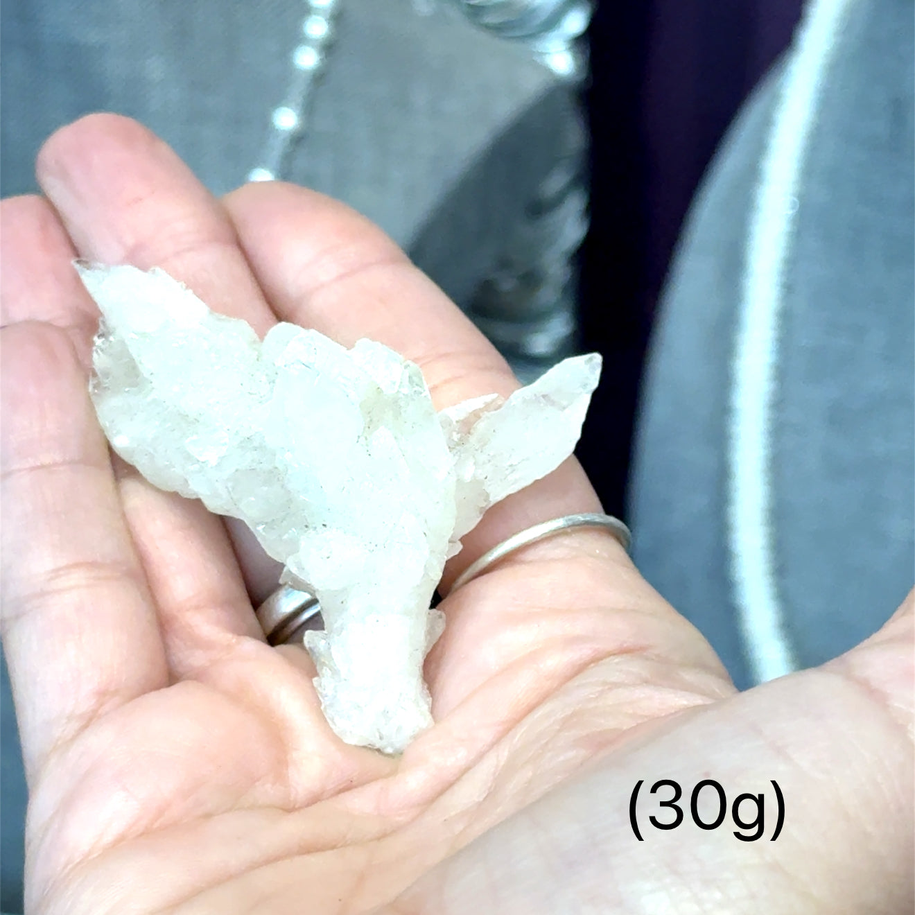 A model holding raw white aragonite specimen gemstones in their hand sizes (30g) on a mixed-colored background, front view.