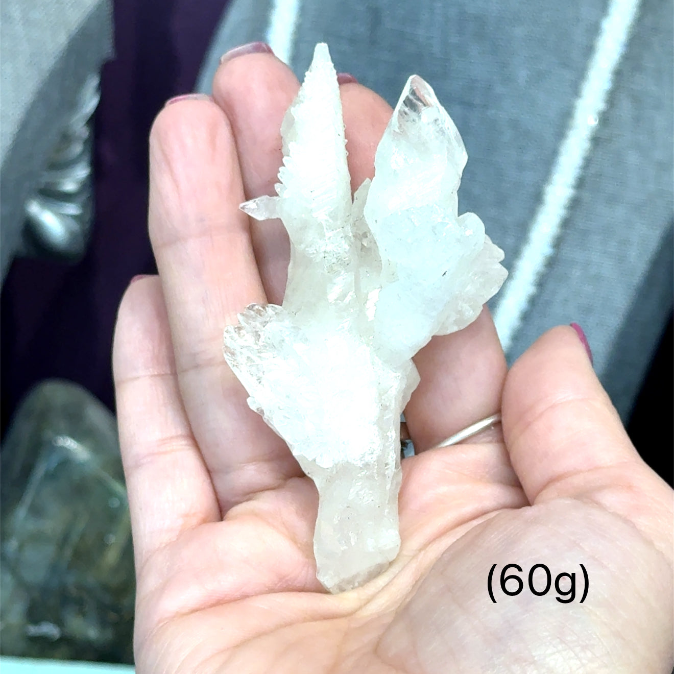 A model holding raw white aragonite specimen gemstones in their hand sizes (60g) on a mixed-colored background, front view.