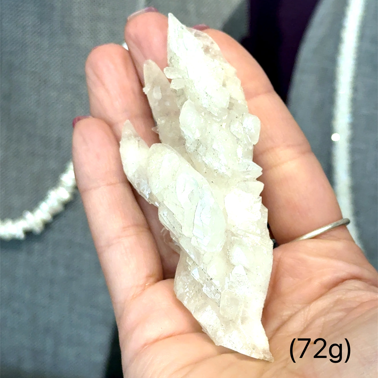 A model holding raw white aragonite specimen gemstones in their hand sizes (72g) on a mixed-colored background, front view.