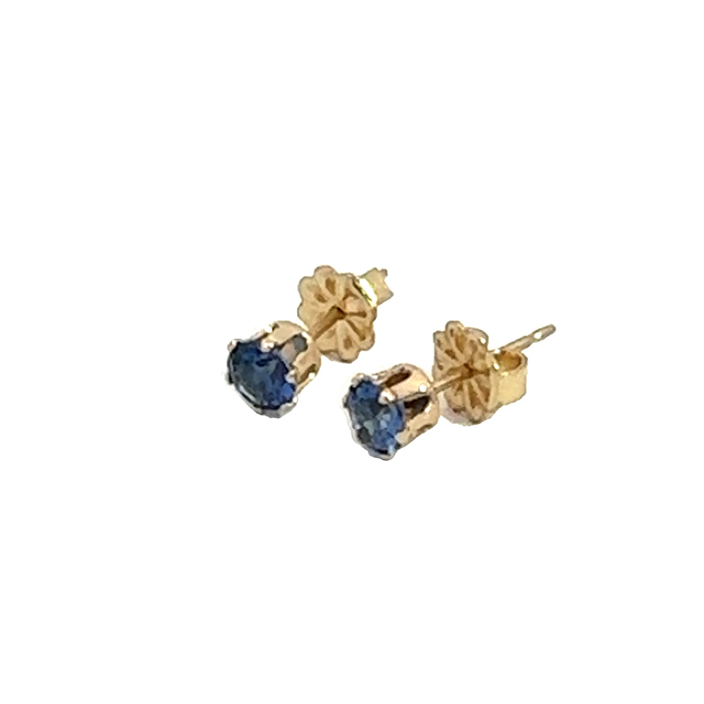 A pair of blue sapphire stud earrings with 14k gold-filled baskets and gold-filled push-backs on a white background, front left angle overview. 