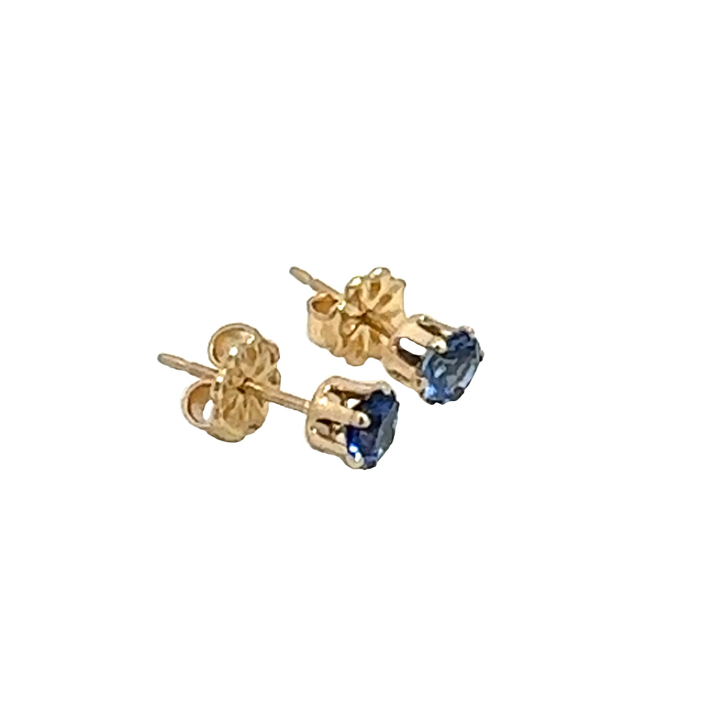 A pair of blue sapphire stud earrings with 14k gold-filled baskets and gold-filled push-backs on a white background, front right angle overview. 