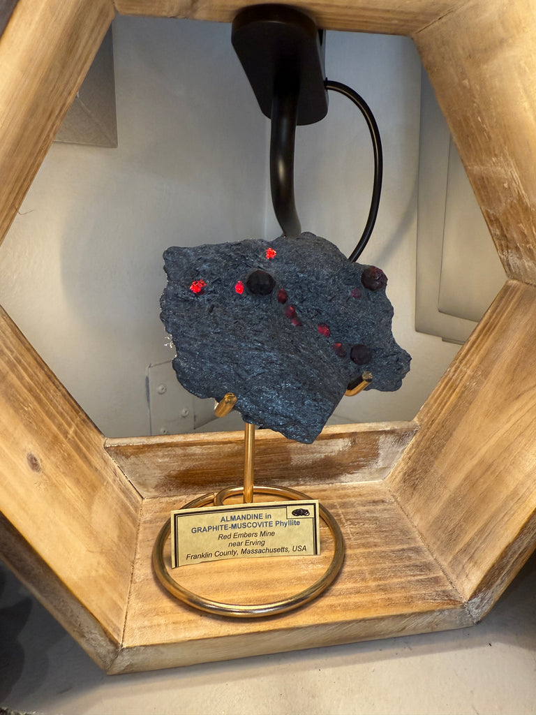 Almandine Garnet Raw Gemstone with Graphite on white displayed with stand and information card lit up front view