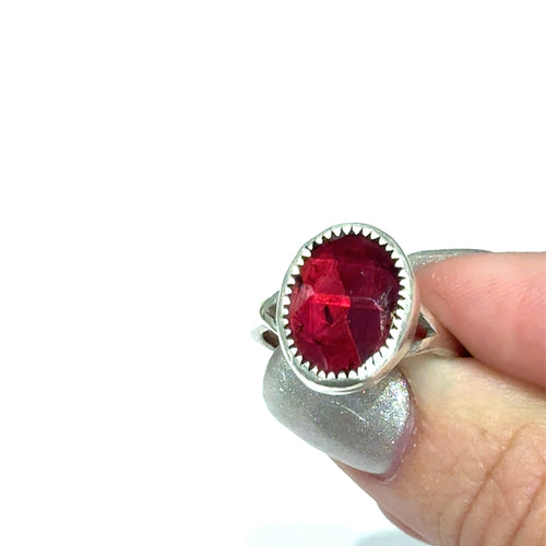 Almandine Garnet gemstone sterling silver ring in a model's finger tips on a white background, front view. 