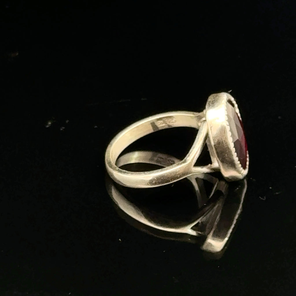 Almandine Garnet gemstone sterling silver ring  on a black background, left side overview. 
