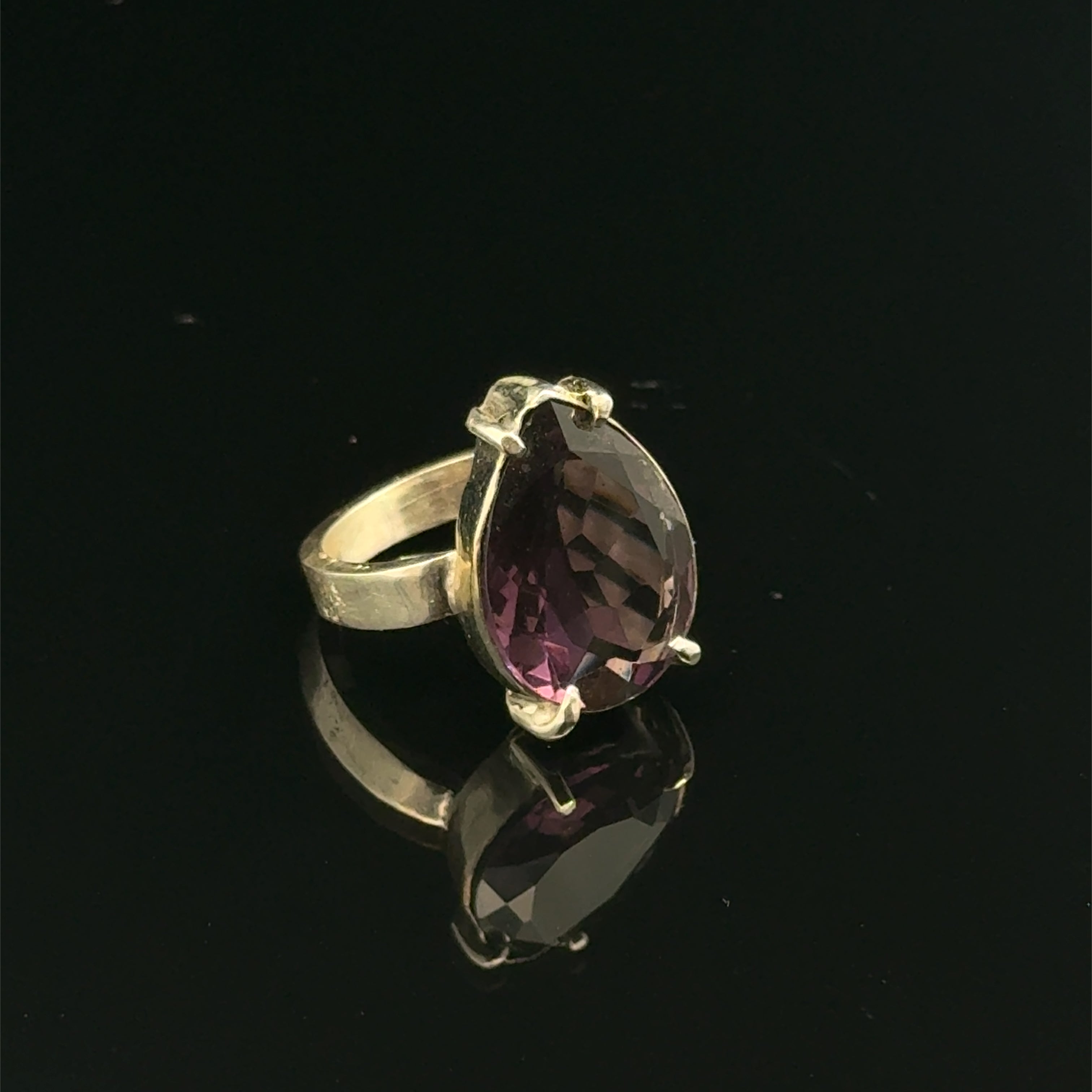An Ametrine Ring with a purple teardrop-shaped gemstone on a  black  background, right side front view.