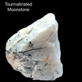 An Extra large raw tourmalinated moonstone specimen 4 pounds with black tourmaline needles through pearlescent white moonstone on a black background, front view. 