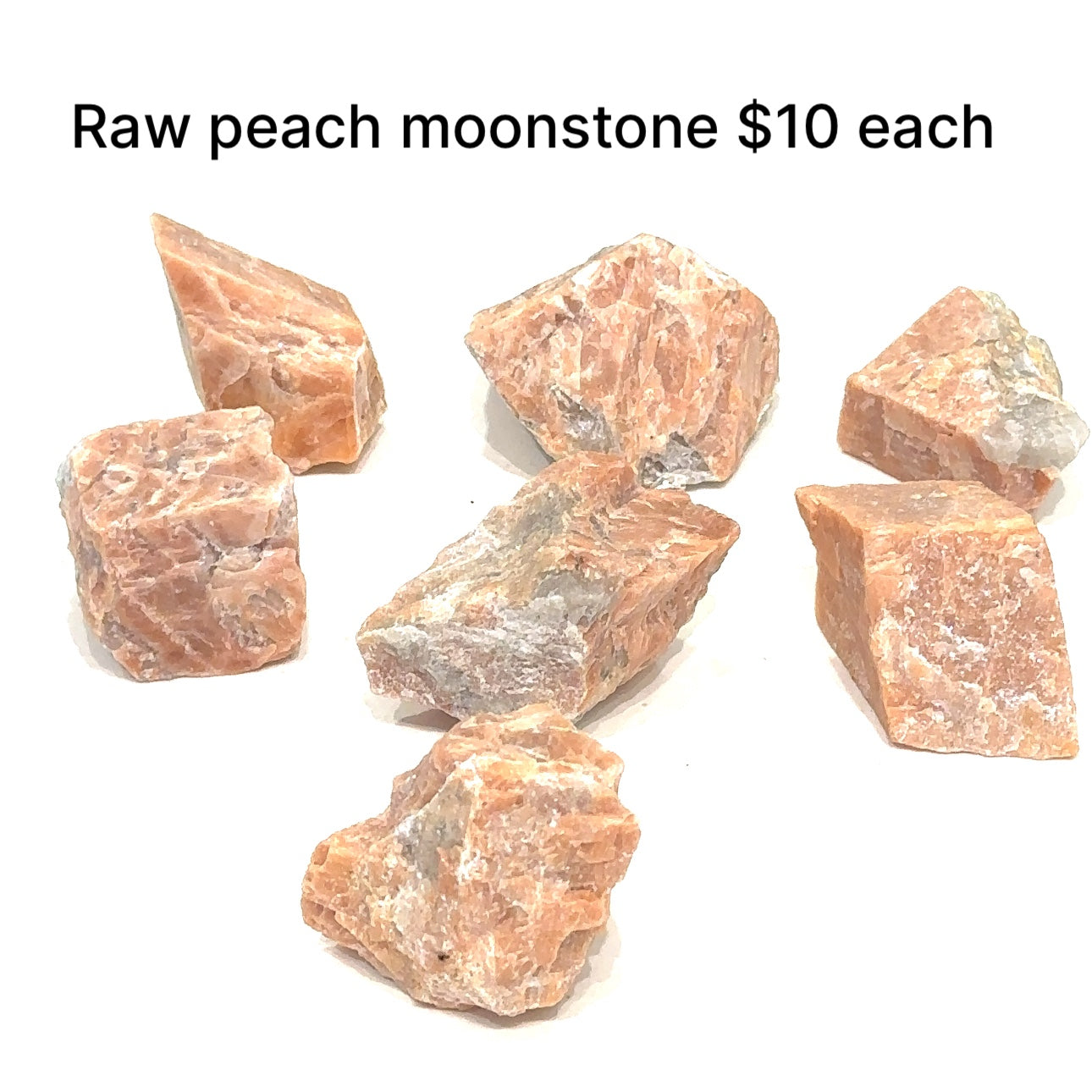 Assorted raw Peach Moonstones arranged together, showing natural color variations and soft feminine glow on white overview