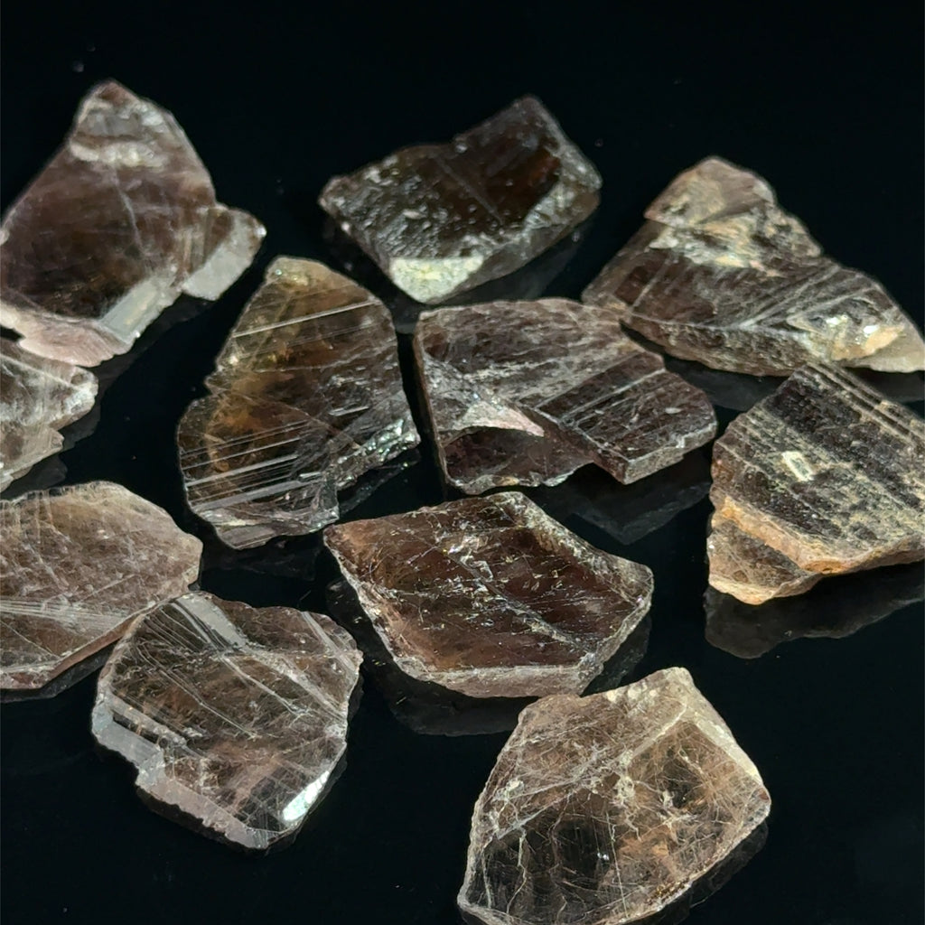 Axinite Raw Gemstones grouping on black 