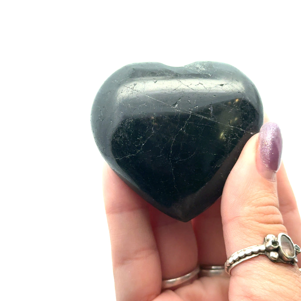 Black Tourmaline gemstone hearts on white  in hand front view