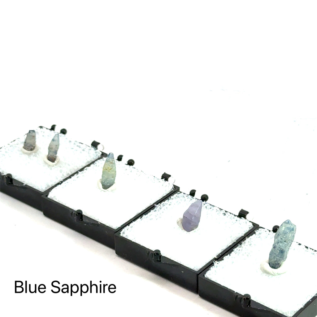 Blue Sapphire raw gemstone on white in perky box grouping up close view