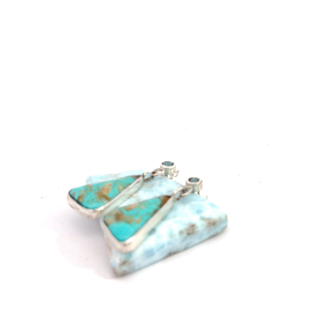 Blue Zircon and Royston Turquoise sterling silver drop earrings — handcrafted by Hidden Jewel South End on a white background lifted by a gemstone front  left side view. 